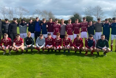 Un grupo de estudiantes de la St. Ciarán’s Community School posan juntos en un campo deportivo con árboles y un cielo nublado de fondo.