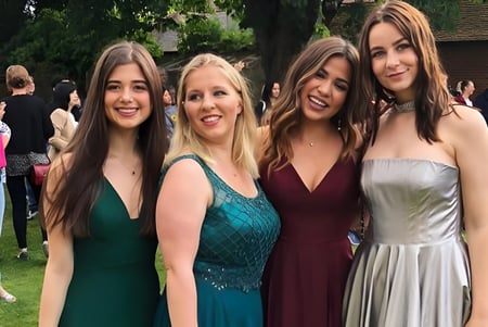 Cuatro alumnas de la St. Clare’s School posan juntas en el verde.