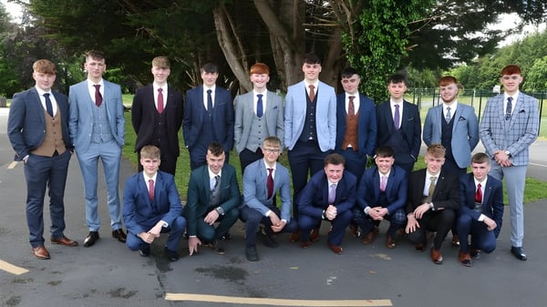 Un grupo de estudiantes de St. Coleman's College está junto en un área parecida a un parque con árboles de fondo.