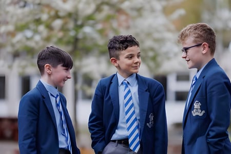 Tres alumnos en uniformes escolares están juntos en el área exterior del St. Colmans College.