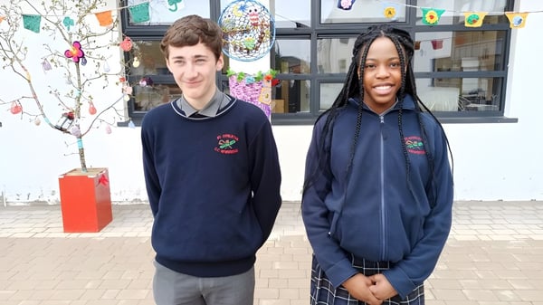 Dos estudiantes están de pie frente al colorido edificio escolar de St. Conleths College.