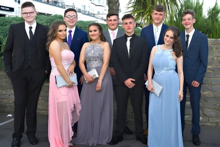 Un grupo de personas posan juntas frente a una pared de ladrillo en el campus de St. Conleths College.