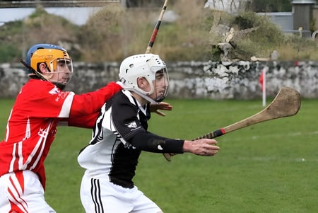 Dos jugadores en ropa deportiva juegan en el campo de deporte de St. Cuan’s College con un fondo de edificio.