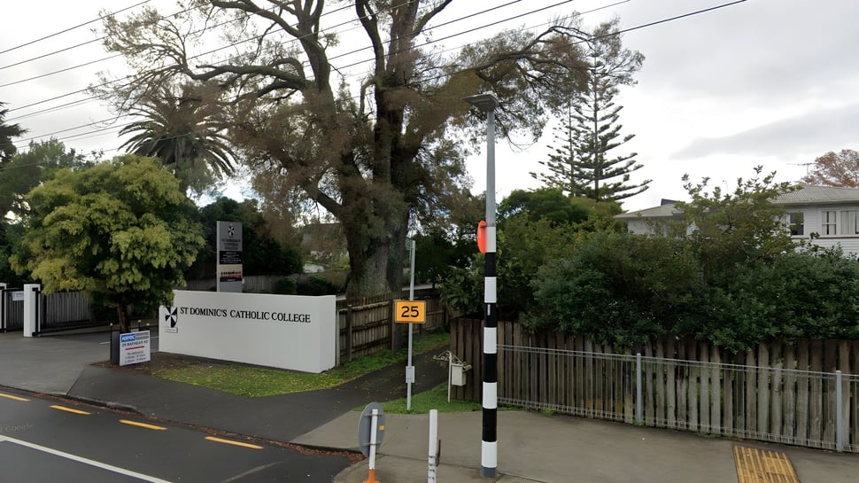 La entrada al campus de St. Dominic's Girl’s Catholic College con un cartel y vegetación circundante.