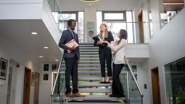 Tres personas están en una escalera en un edificio moderno en el campus de la St. Dominic's Grammar School.
