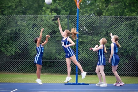 Estudiantes de la St. Dominic's Grammar School realizan una rutina deportiva sincronizada en una cancha de tenis.