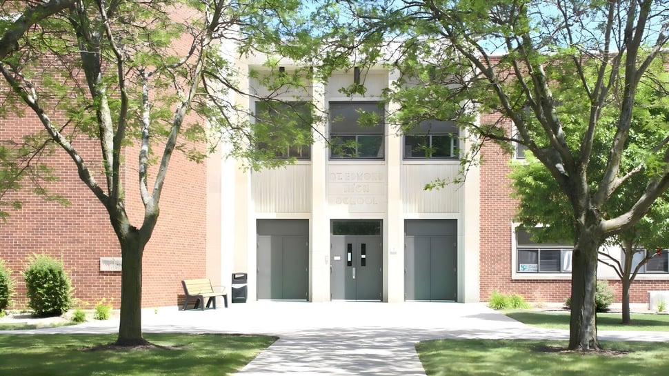 El moderno edificio de ladrillo con grandes ventanas de St. Edmond Catholic School está rodeado de vegetación y árboles.