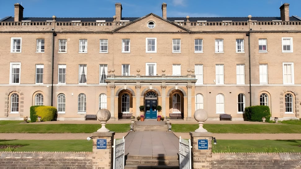 El impresionante edificio principal de St. Edmund’s College está rodeado de jardines cuidados con caminos de piedra y macetas decorativas.