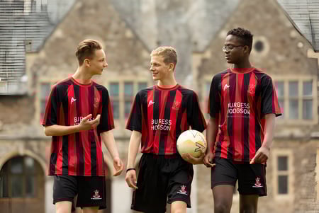 Tres estudiantes de la St. Edmunds School están delante de un edificio histórico con ventanas de arco.