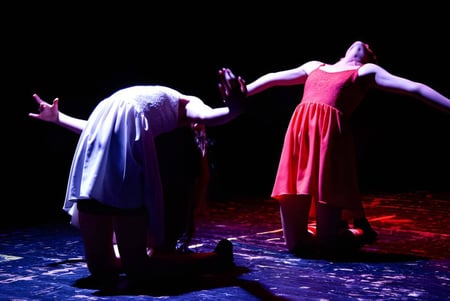 Estudiantes de la St. Edward's School en Poole presentan una obra de teatro dramática en un escenario con suelo estampado.