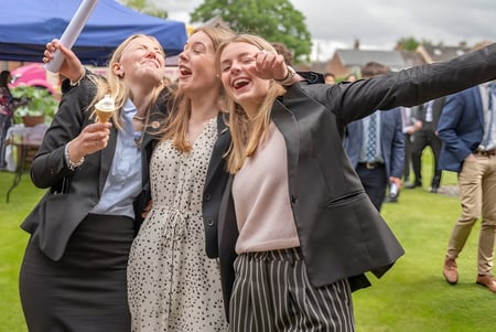 Alumnas de la St. Felix School se hacen un selfie al aire libre frente a un campo con carpas.