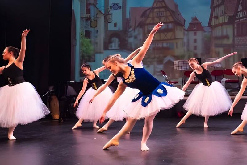 Un grupo de bailarinas de ballet de St. George's Ascot se presenta en un escenario con una silueta de ciudad europea de fondo.