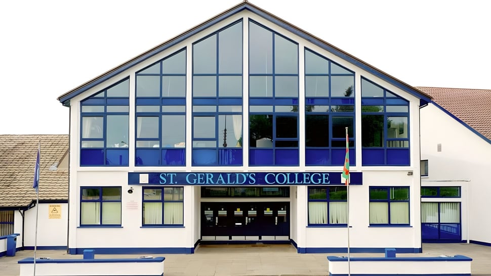 El moderno edificio de vidrio con la inscripción St. Gerald's College está rodeado de un área pavimentada.