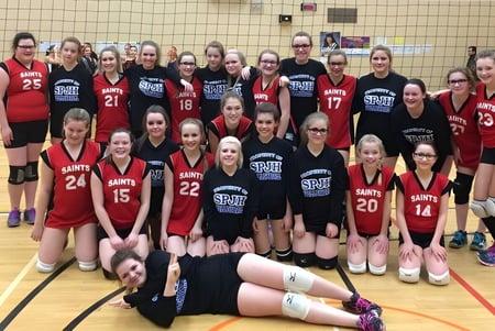 El equipo de baloncesto femenino de la St. James' Regional High posa junto en la cancha de baloncesto con camisetas rojas y negras.