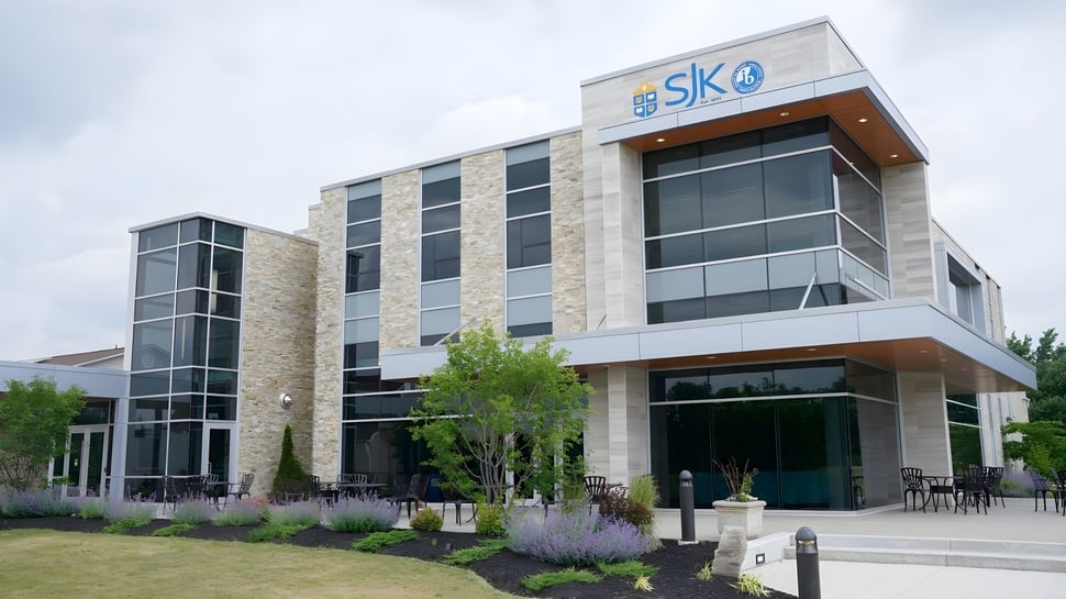 El moderno edificio de varios pisos con el logo de SKO en el campus de la St. John’s-Kilmarnock School está rodeado de áreas verdes y zonas de descanso.