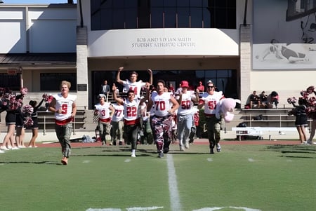 Un grupo de estudiantes está de pie como equipo deportivo en el campo de deportes frente al edificio de la St. John's School.