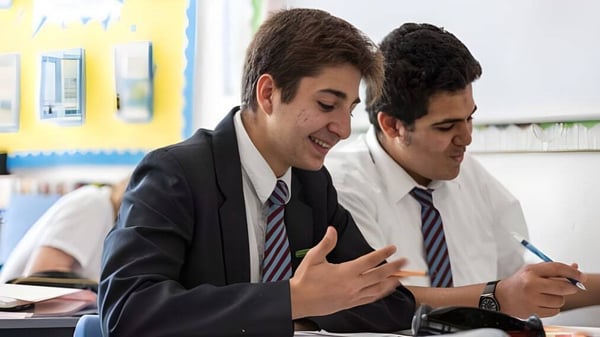Dos estudiantes de la St. John’s School Sidmouth trabajan juntos en una tarea en el escritorio.