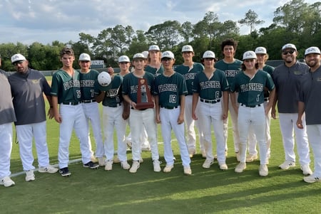 Un grupo de jugadores de béisbol en uniformes está en el campo de la St. Joseph Academy.