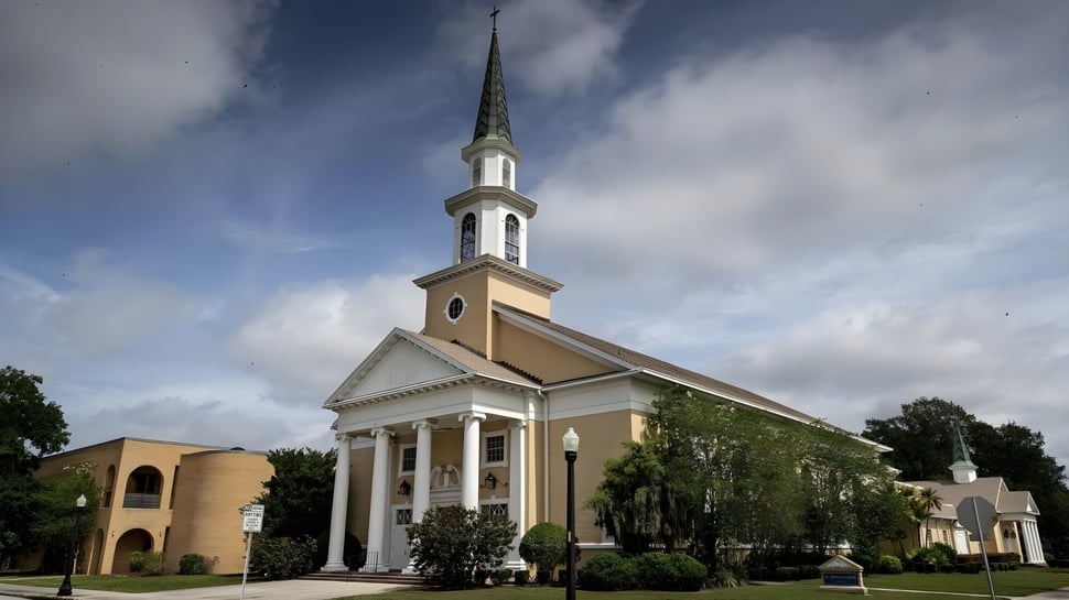 La iglesia blanca con alto torre se encuentra en el terreno de la St. Joseph Academy rodeada de áreas verdes y otros edificios.