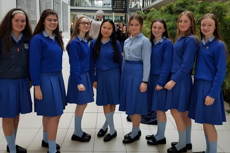 Un grupo de alumnas con uniformes azules está juntas en un interior en el campus de la St. Joseph of Cluny.