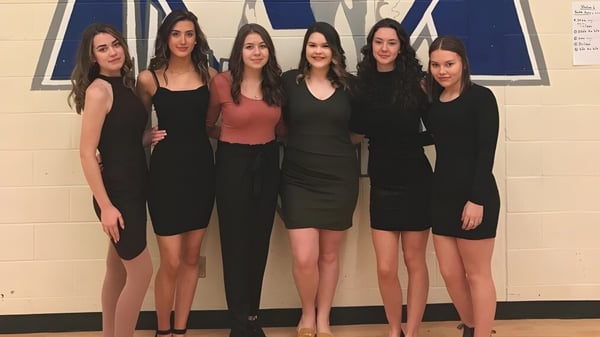 Seis alumnas de St. Kevin's High School en atuendos negro-rojos frente a un fondo azul-blanco.