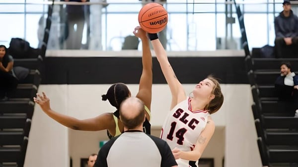 Un jugador de baloncesto con camiseta roja salta para lanzar durante el juego en el campus del St. Lawrence College.