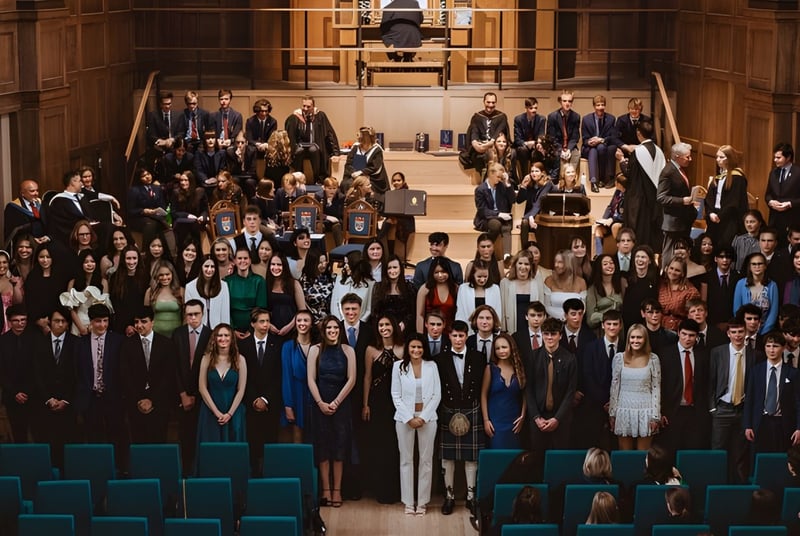 Un gran grupo de estudiantes de la St. Leonards School en ropa académica se reúne en un magnífico salón para la ceremonia de graduación.