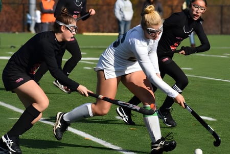 Estudiantes del St. Leo’s College juegan un partido de hockey sobre campo en el césped verde.
