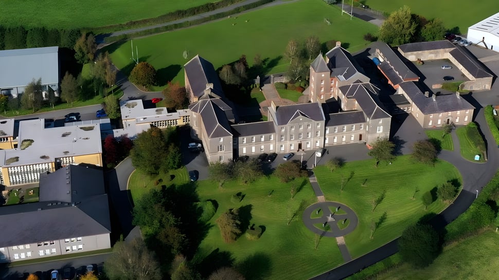 Un gran edificio histórico parecido a un castillo se encuentra en una colina cubierta de hierba en el campus de St. Macartan's College.
