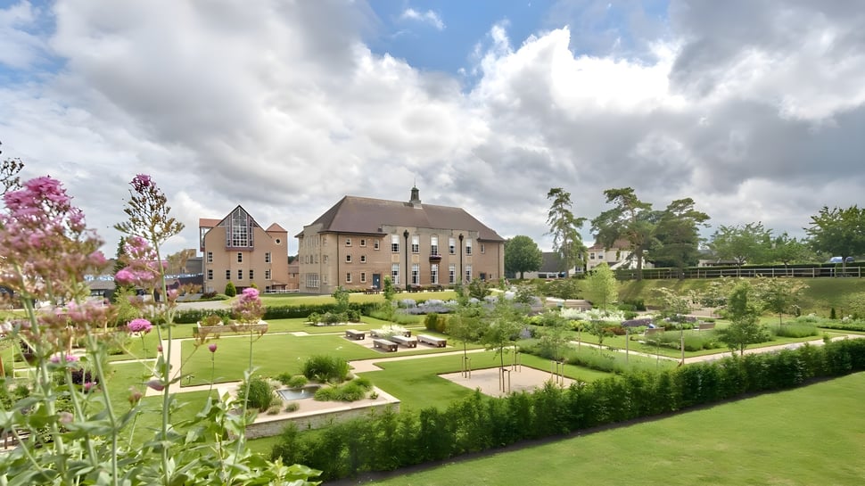 El edificio histórico de St. Mary's Calne está rodeado de un jardín cuidado con flores de colores y setos recortados.
