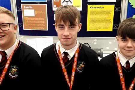 Tres alumnas y alumnos en uniforme escolar están frente a un tablón de anuncios en el campus de St. Mary’s College Ballysadare.