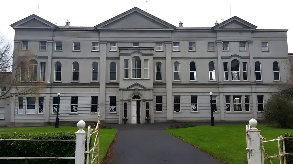 El magnífico edificio principal de St. Mary’s College con fachada simétrica y varios frontones se encuentra detrás de un área verde cercada.