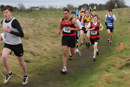 Corredores compiten en un sendero boscoso cubierto de hierba durante la competencia de corrida del St. Marys College Galway.