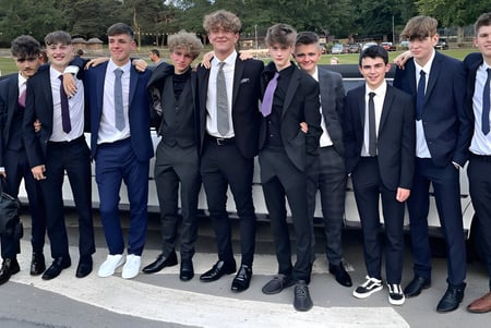 Un grupo de chicos en ropa formal está de pie en el área exterior de la St. Mary’s Diocesan School con árboles y edificios de fondo.