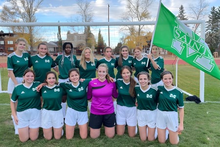 Un grupo de jóvenes futbolistas está junto en el campo de fútbol de la St. Mary's High School.