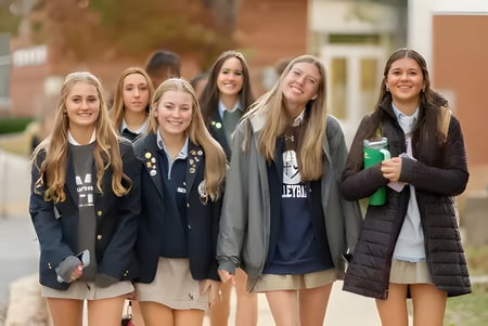 Un grupo de estudiantes se encuentra junto y sonríe en el campus de St. Mary's Ryken High School.