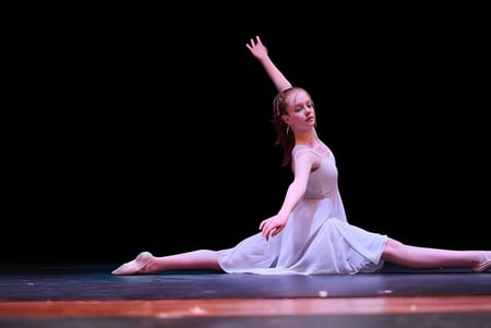 Una bailarina en un vestido blanco realiza una actuación en el escenario de la St. Mary's School.