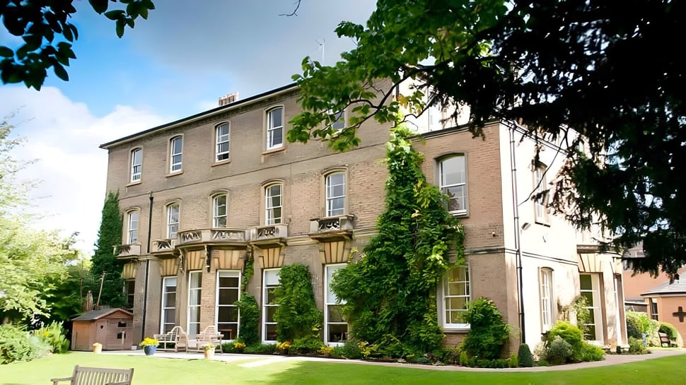 El edificio de ladrillo de varios pisos de la St. Mary's School está rodeado de árboles y vegetación cuidada.