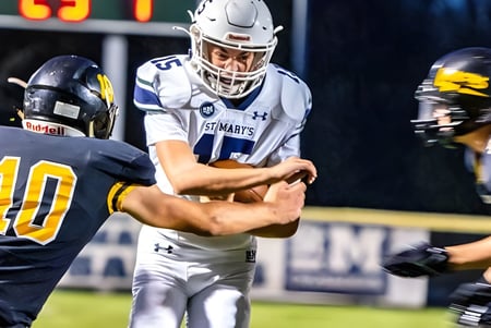 Dos jugadores de fútbol en diferentes camisetas luchan en el campo de la St. Mary's School por el balón.