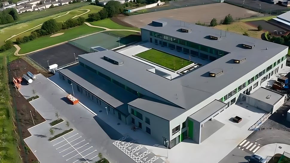 El moderno edificio de varios pisos con techo verde en el campus de St. Mary’s Secondary está rodeado de áreas de césped.