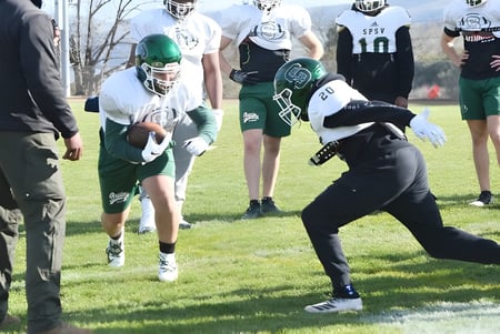 Un grupo de jugadores de fútbol de St. Patrick's High School entrena en un campo de césped.