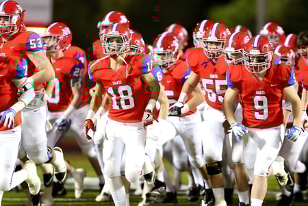 Un grupo de futbolistas de la St. Paul High School está de pie por la noche en el campo de un estadio.