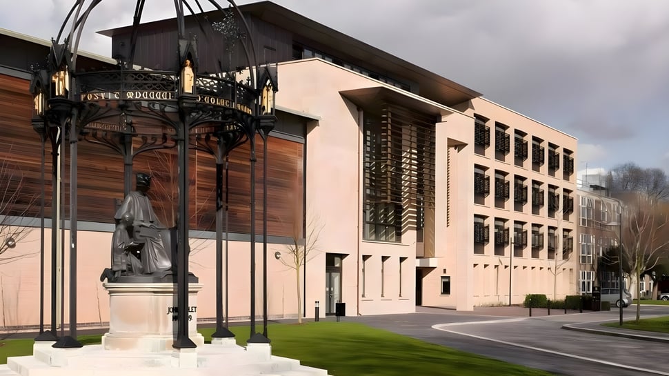 El histórico edificio de la St. Paul’s School con una estatua en primer plano y un entorno urbano.