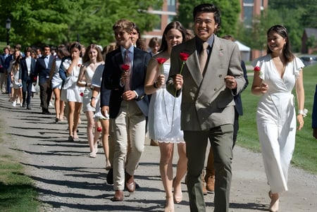 Un grupo de personas camina por un camino rodeado de plantas verdes en el campus de St Paul’s School.