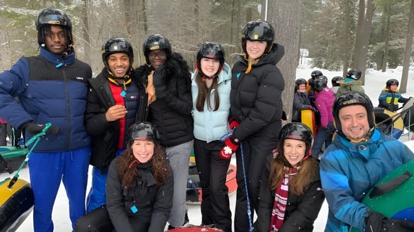 Un grupo de estudiantes de la St. Peter Catholic High School está en el bosque nevado y lleva ropa de invierno y cascos.