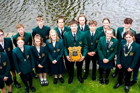 Estudiantes en uniformes escolares están juntos afuera junto al agua en el terreno de St. Peter's College.