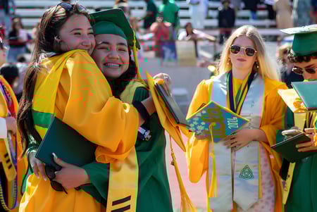 Estudiantes de la St. Peter’s High School en coloridas togas de graduación se agrupan durante la ceremonia de graduación.
