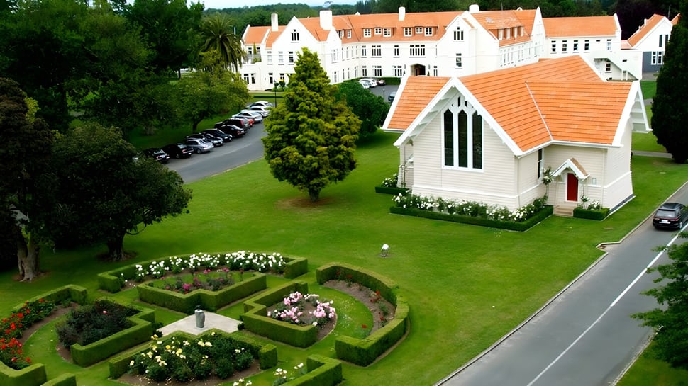 El histórico edificio principal de St. Peter's School Cambridge rodeado de un jardín cuidado con parterres de flores y caminos.