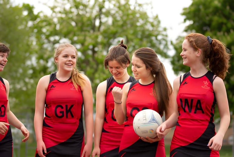 Un grupo de jóvenes deportistas en camisetas rojas con un balón de rugby en el campo de la St. Peters School.