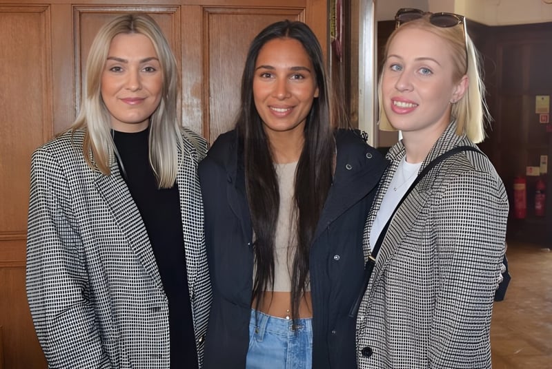 Tres alumnas posan frente a una pared de madera en el campus de St. Teresa’s College.